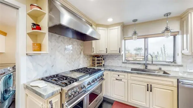 a kitchen with stainless steel appliances a sink a stove and a window