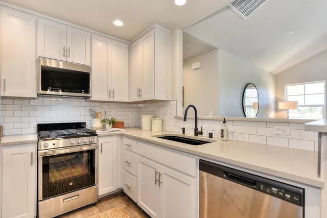 a kitchen with appliances a sink cabinets and a window