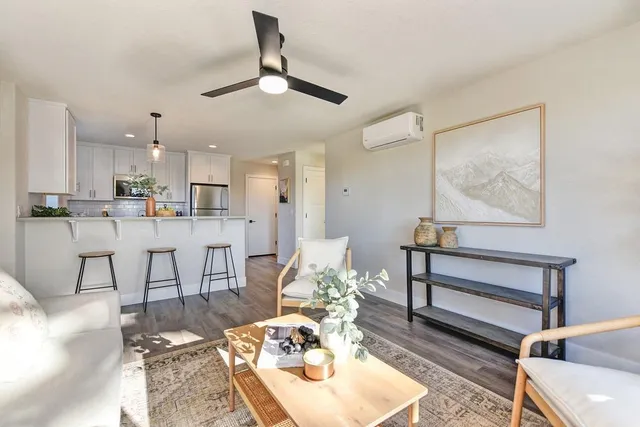 a living room with stainless steel appliances kitchen island granite countertop furniture and a rug