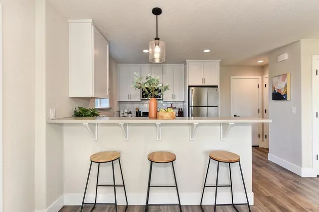 a kitchen with stainless steel appliances a dining table chairs sink and cabinets