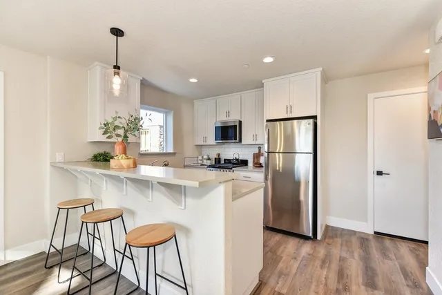 a kitchen with stainless steel appliances granite countertop a refrigerator a stove a sink dishwasher and a refrigerator with wooden floor