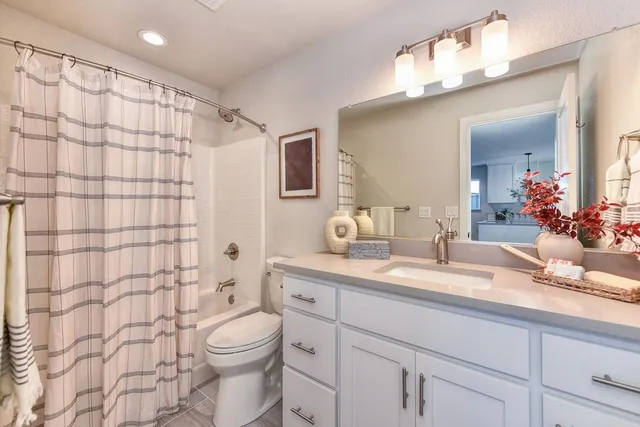 a bathroom with a granite countertop sink a toilet and shower curtain