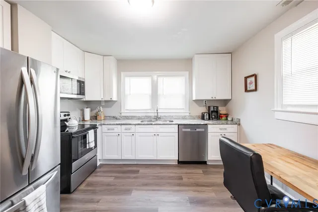 a kitchen with granite countertop white cabinets and stainless steel appliances