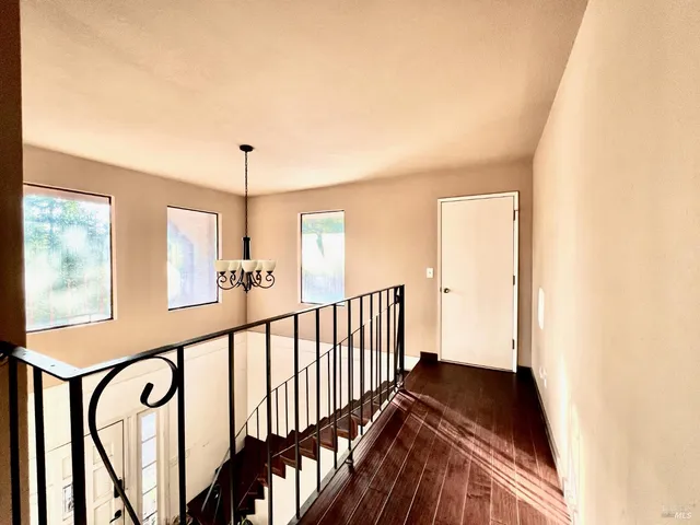 a view of a hallway with wooden floor and staircase
