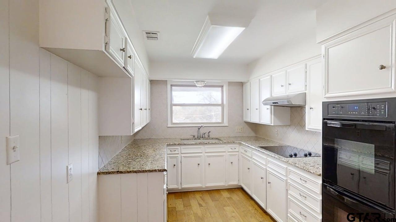 17035 Deer Run Road Flint, TX 75762 - Photo 6 of 31 a kitchen with granite countertop a sink stainless steel appliances white cabinets and a window