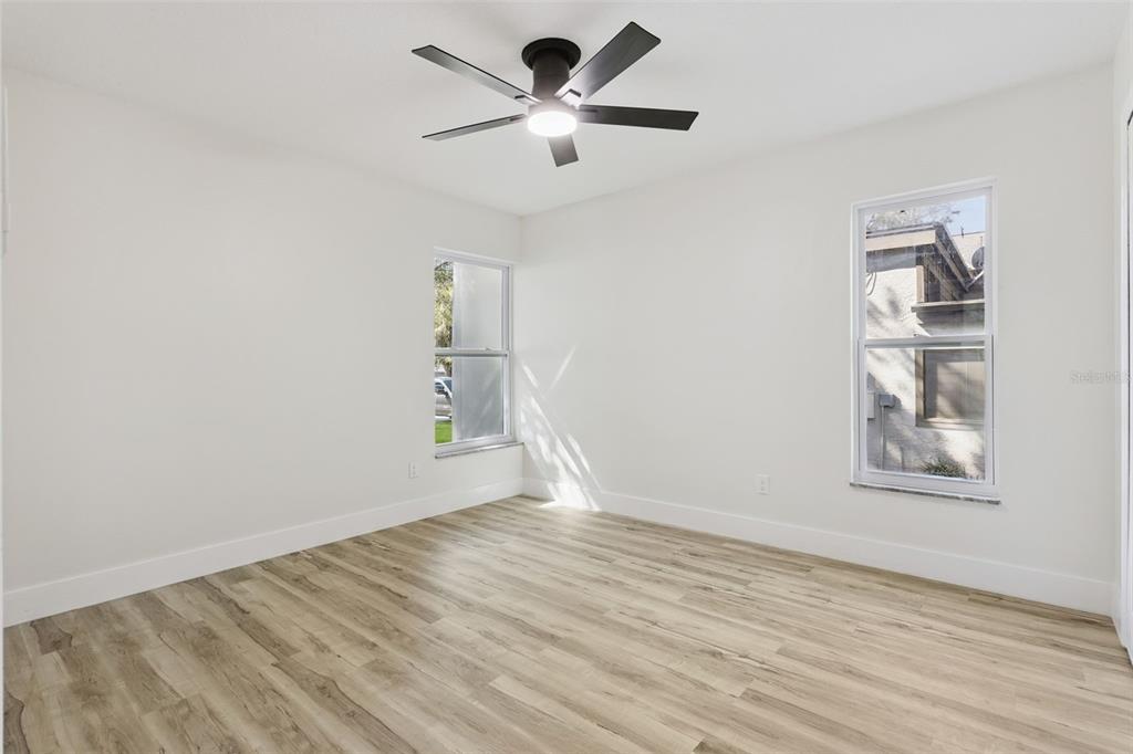 407 Forest Road Mount Dora, FL 32757 - Photo 18 of 35 an empty room with wooden floor chandelier fan and windows