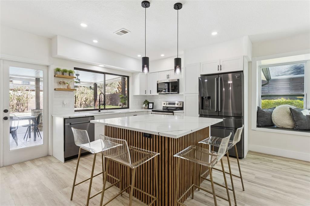 407 Forest Road Mount Dora, FL 32757 - Photo 8 of 35 a kitchen with stainless steel appliances kitchen island granite countertop a refrigerator a stove a sink a dining table and chairs with wooden floor