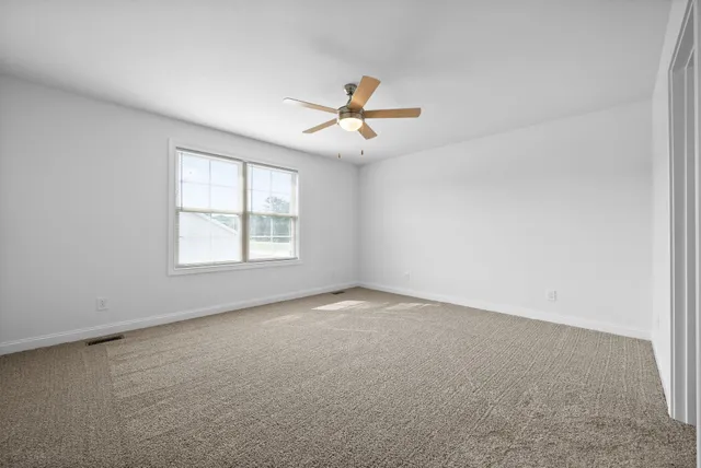 an empty room with closet and a ceiling fan