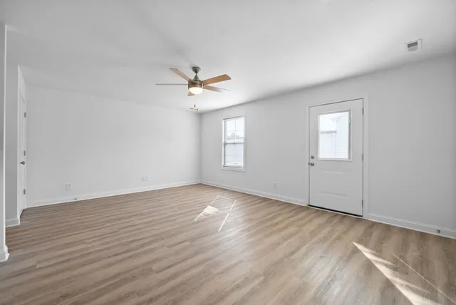 a view of an empty room with a window and wooden floor