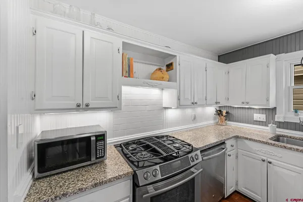 a kitchen with granite countertop a stove sink and cabinets
