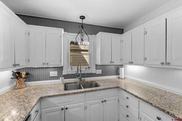 a kitchen with granite countertop a sink stainless steel appliances and white cabinets