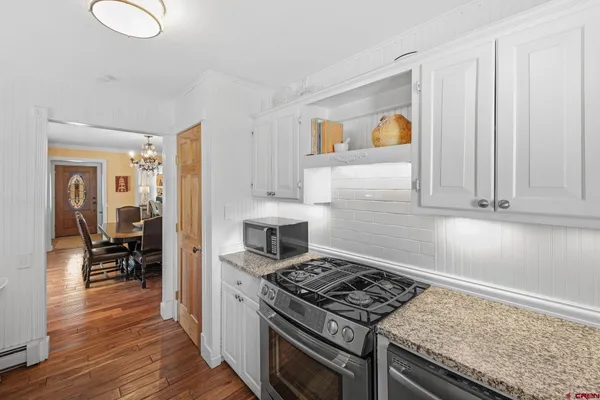 a kitchen with granite countertop wooden cabinets a stove and a wooden floor