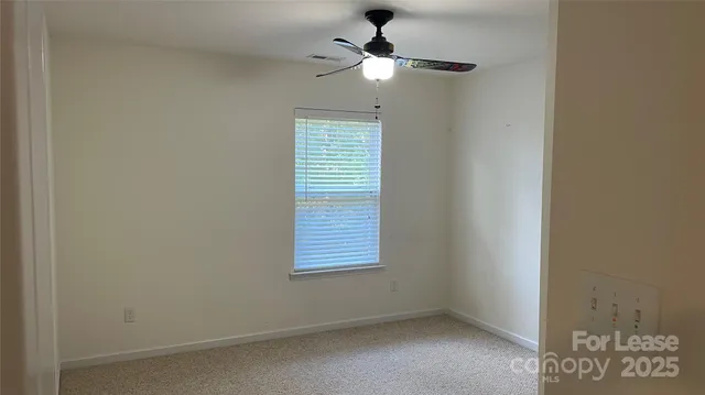 an empty room with a window and a ceiling fan