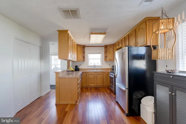 a kitchen with stainless steel appliances a refrigerator a sink dishwasher a stove with wooden floor