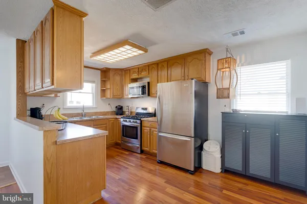 a kitchen with granite countertop stainless steel appliances a refrigerator cabinets and wooden floor