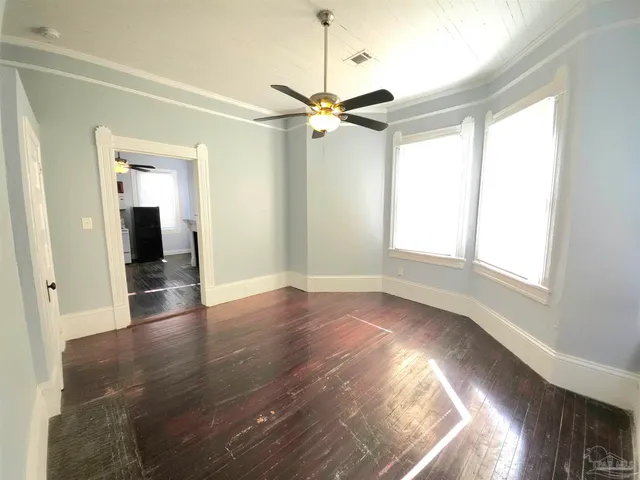 a view of empty room with wooden floor and fan