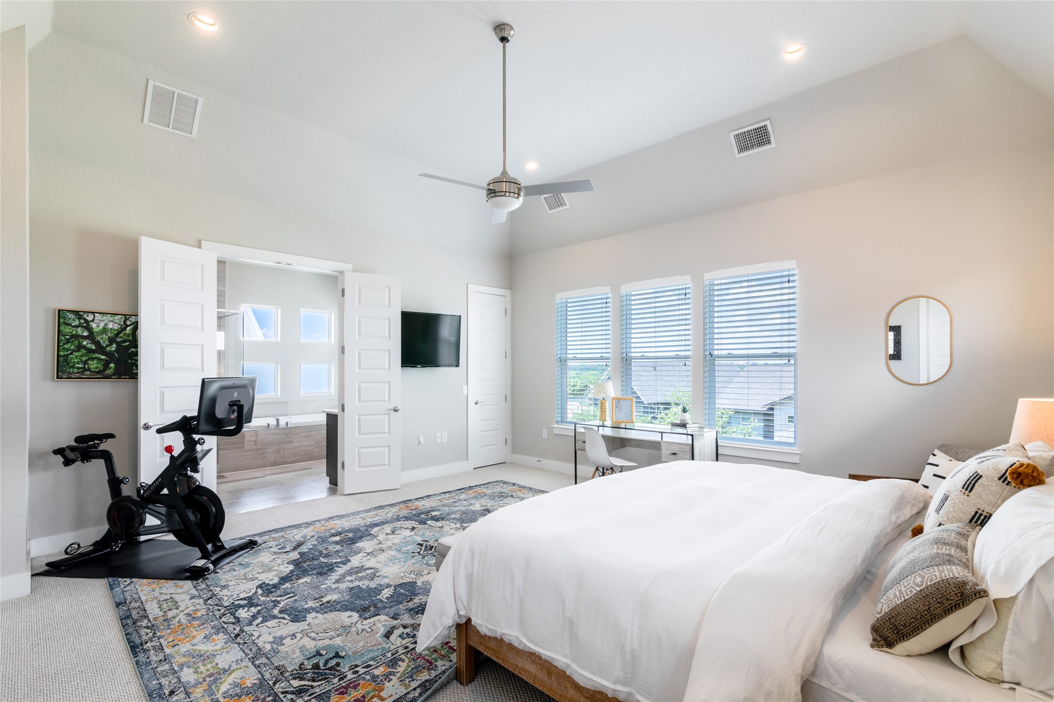 6025 Seville Drive Austin, TX 78724 - Photo 13 of 40 Spacious primary bedroom featuring high ceiling with a ceiling fan, recessed lighting, and soft gray carpeting with view to the primary bathroom