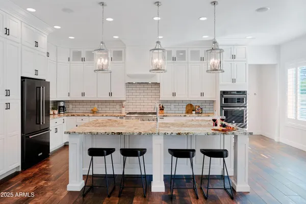 a kitchen with stainless steel appliances granite countertop a table and chairs in it