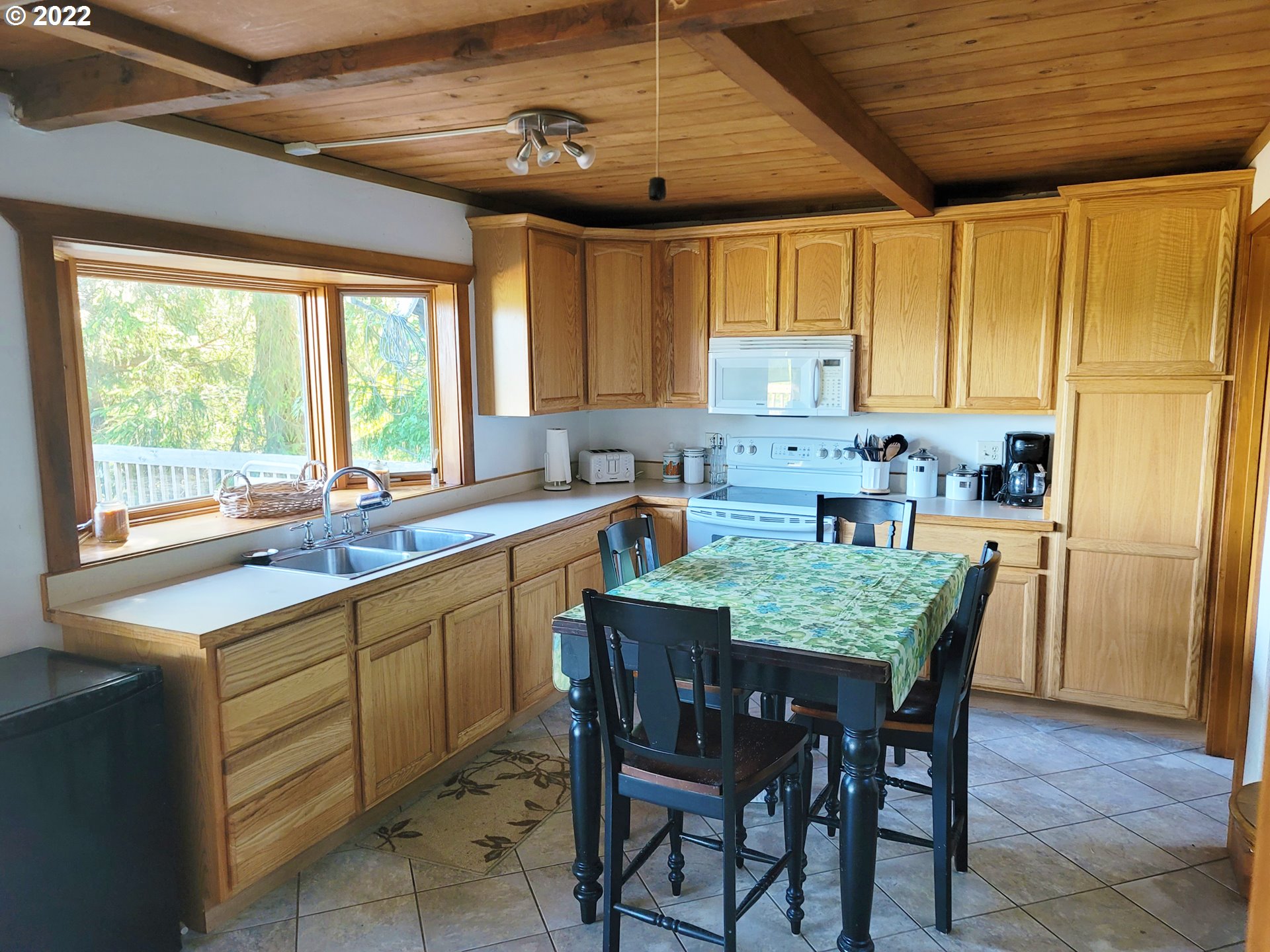 5529 Herman Cape Road Florence, OR 97439 - Photo 4 of 17 a kitchen with a stove a sink dishwasher a dining table and chairs with wooden floor