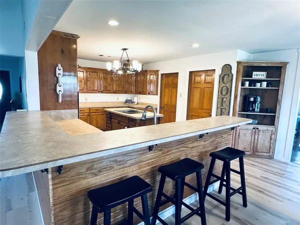 a kitchen with stainless steel appliances granite countertop a refrigerator a sink dishwasher a stove and white countertops with wooden floor