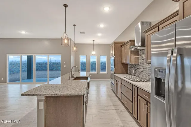 a kitchen with stainless steel appliances granite countertop a refrigerator a sink and a stove