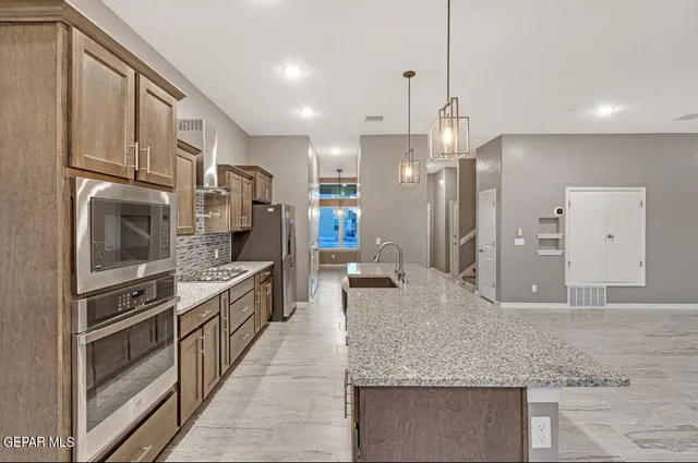 a large kitchen with stainless steel appliances kitchen island granite countertop a refrigerator a stove and a sink