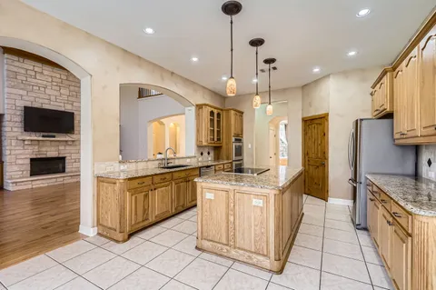 a kitchen with stainless steel appliances granite countertop a stove top oven a sink and a refrigerator