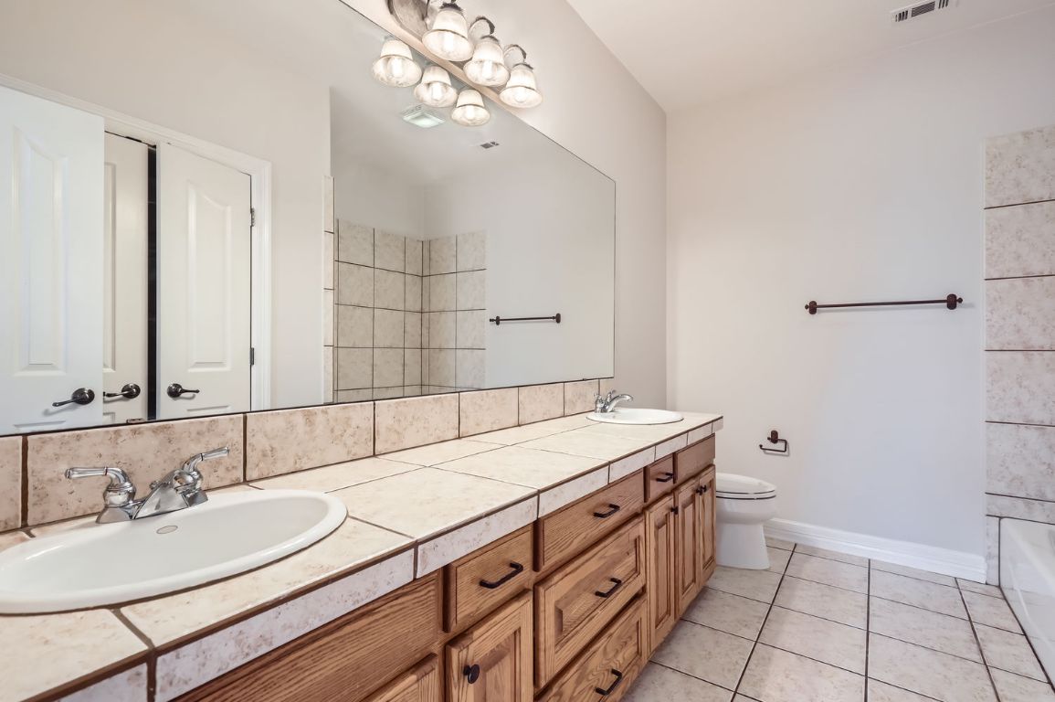 210 Amandas Way Leander, TX 78641 - Photo 23 of 38 Bathroom featuring double vanity, visible vents, toilet, a sink, and tile patterned flooring