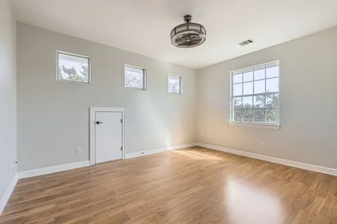 a view of an empty room with a window and wooden floor
