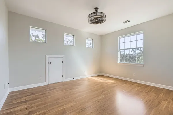 a view of an empty room with a window and wooden floor