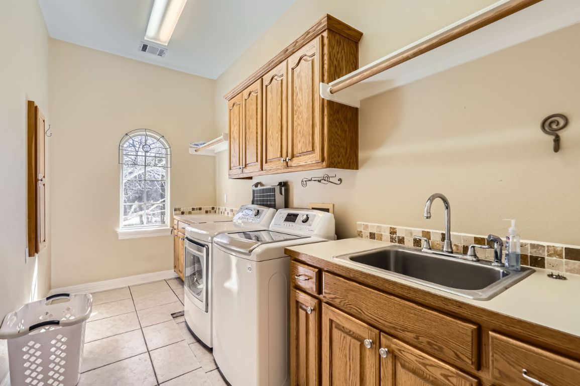 210 Amandas Way Leander, TX 78641 - Photo 31 of 38 Laundry area with light tile patterned flooring, a sink, visible vents, independent washer and dryer, and cabinet space
