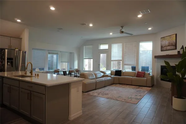 a large living room with stainless steel appliances granite countertop a couch a fireplace a flat screen tv and a couch