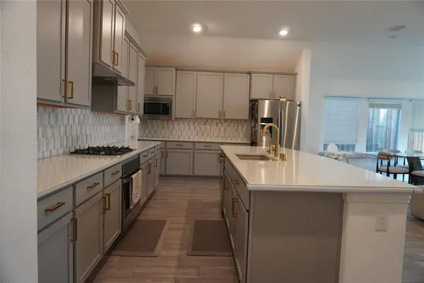 a kitchen with kitchen island granite countertop a sink a counter top space stainless steel appliances and cabinets