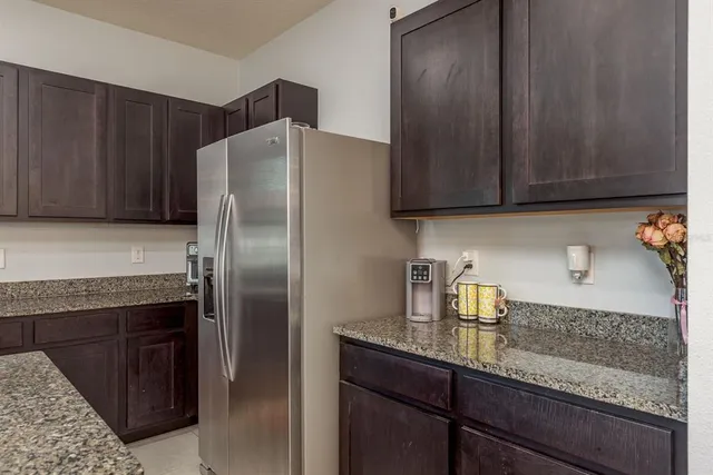 a kitchen with granite countertop stainless steel appliances a refrigerator and cabinets