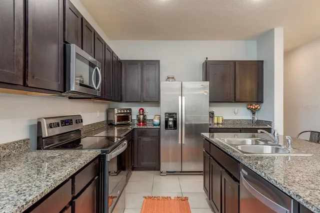 a kitchen with stainless steel appliances granite countertop a sink stove microwave refrigerator and cabinets
