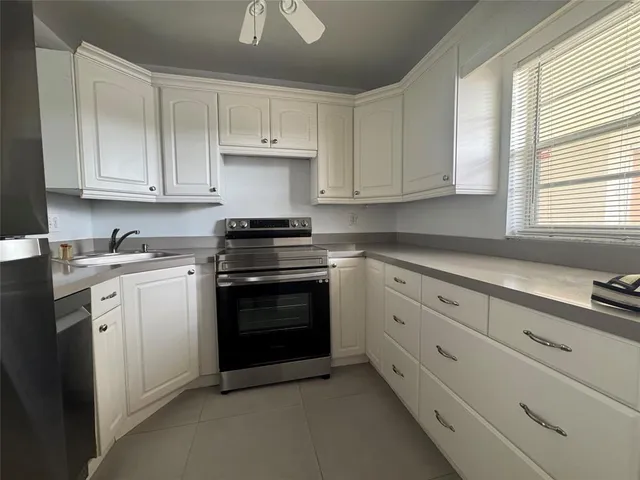 a kitchen with granite countertop white cabinets and stainless steel appliances