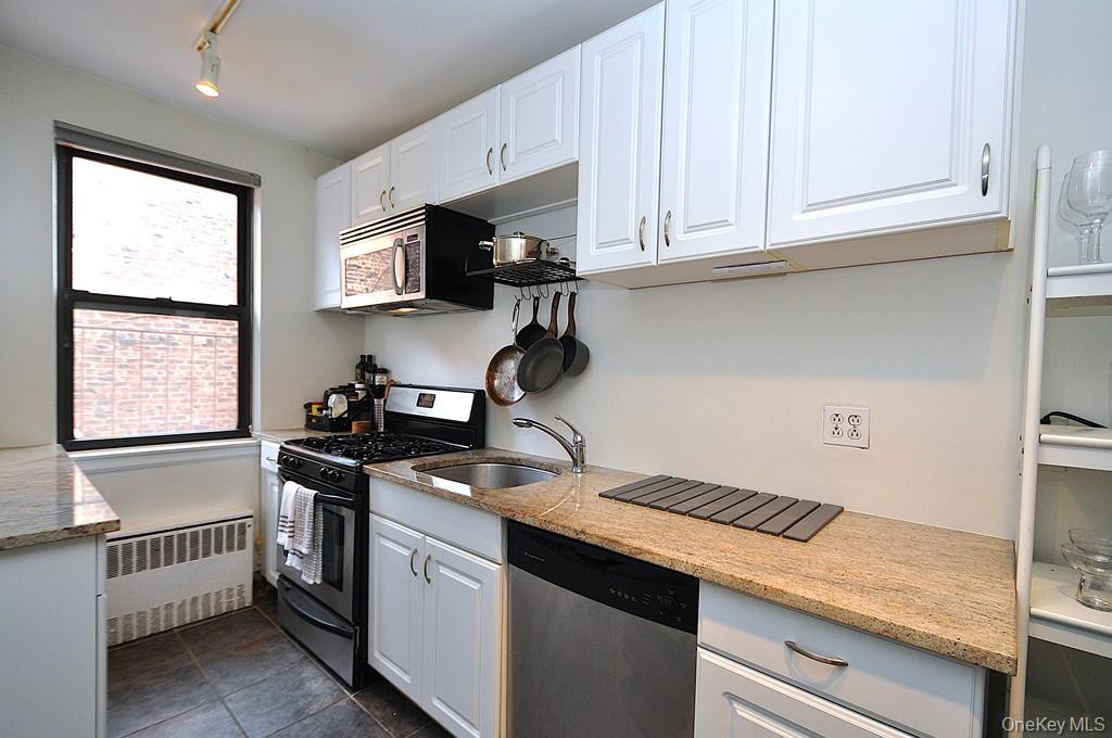 a kitchen with stainless steel appliances granite countertop white cabinets and window