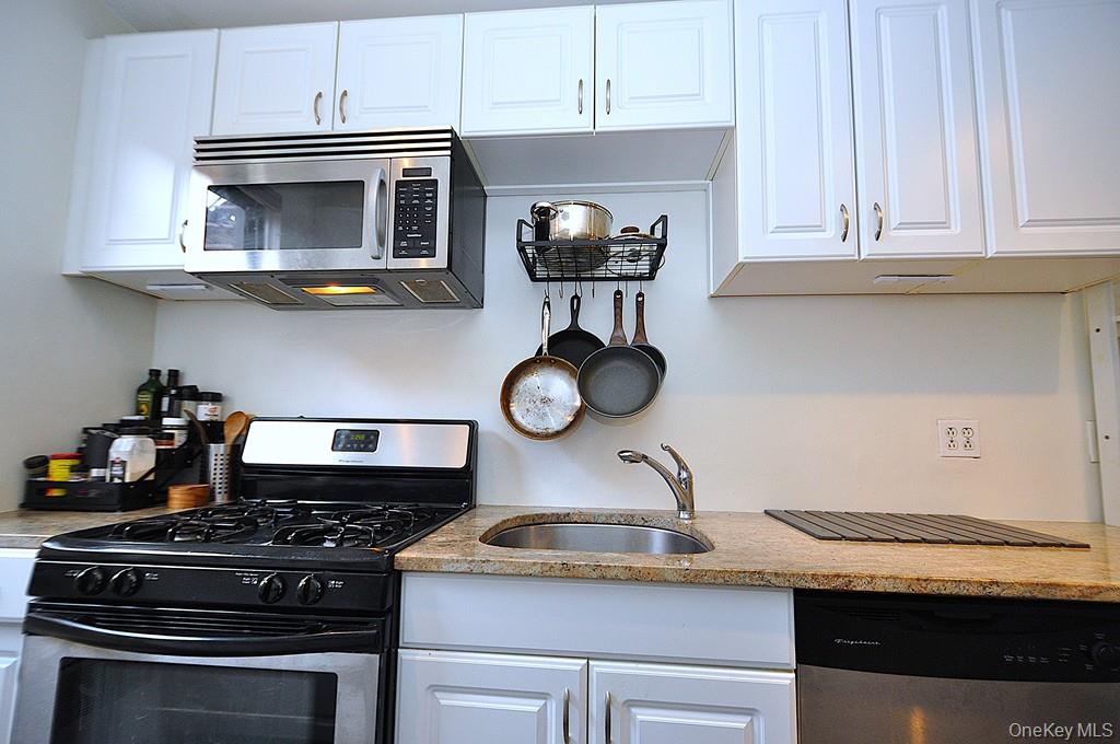 142 Garth Road, Unit 1A Scarsdale, NY 10583 - Photo 13 of 34 a kitchen with stainless steel appliances granite countertop a stove and a microwave