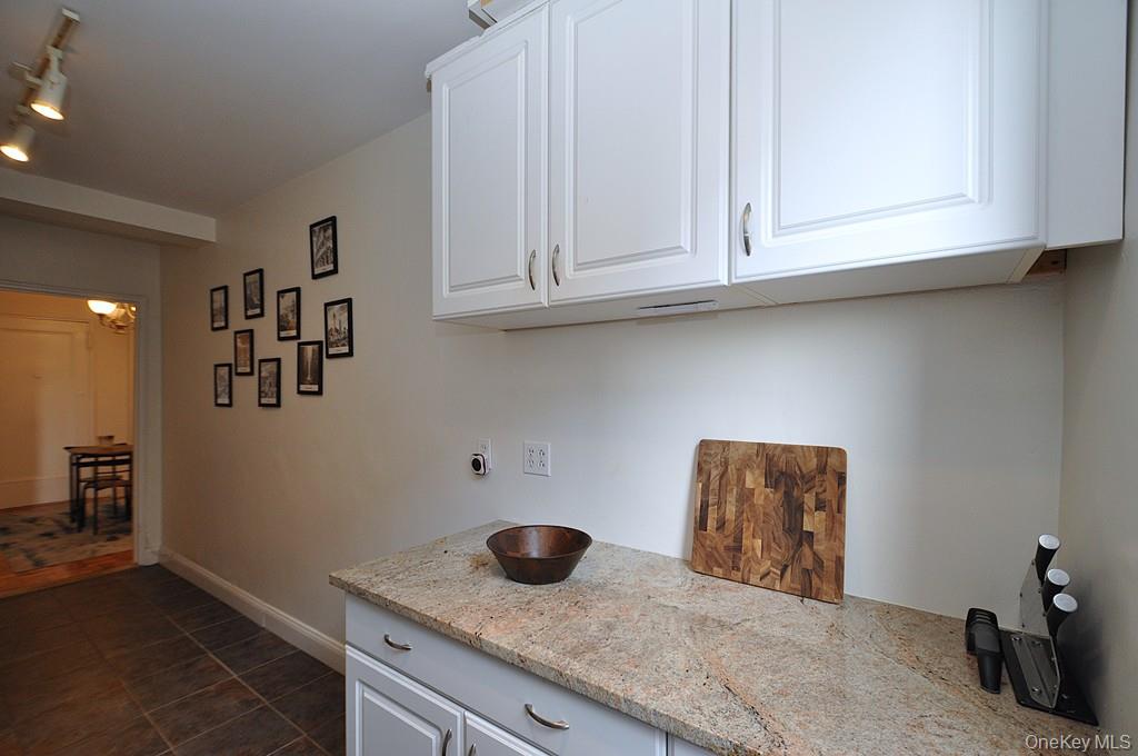 142 Garth Road, Unit 1A Scarsdale, NY 10583 - Photo 10 of 34 a kitchen with granite countertop white cabinets and a wooden floor