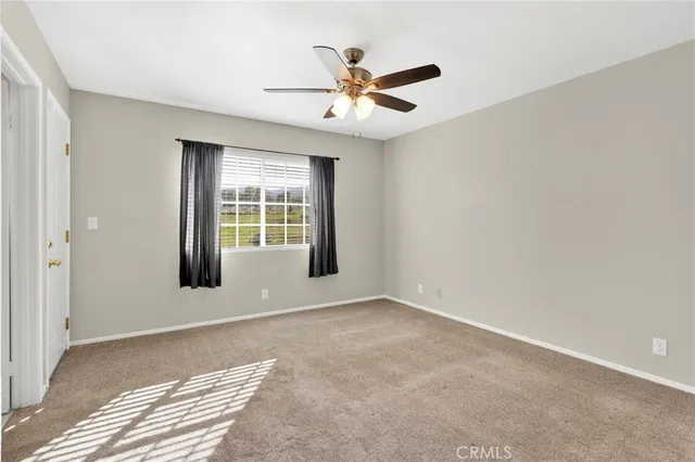 a view of an empty room and chandelier fan