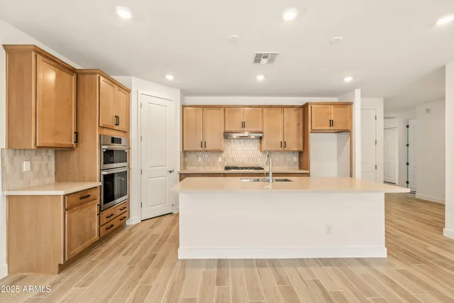 a large kitchen with stainless steel appliances a large counter top a stove and a refrigerator