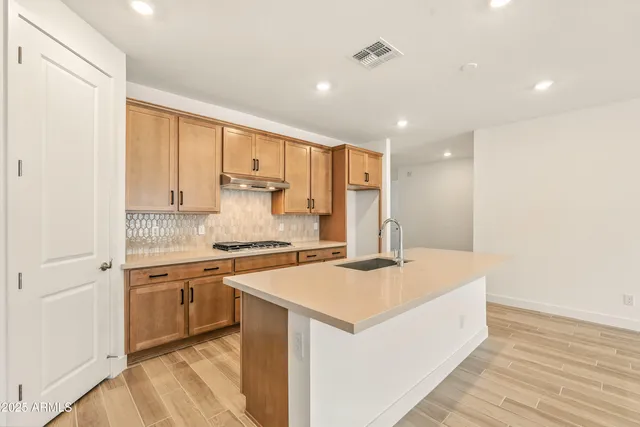 a large kitchen with stainless steel appliances granite countertop a stove a sink and white cabinets with wooden floor