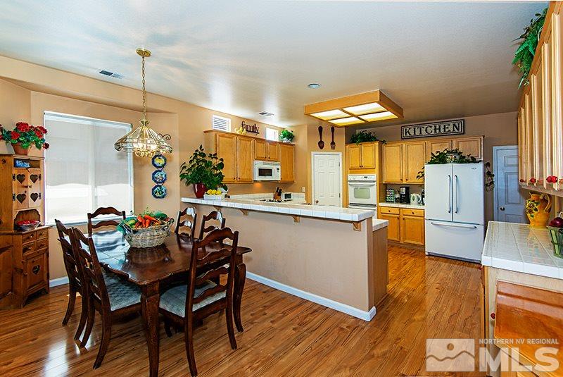 9628 Rolling Rock Way Reno, NV 89521 - Photo 9 of 23 a kitchen with stainless steel appliances wooden floor dining table and chairs