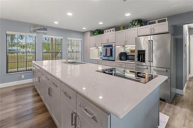 a large kitchen with stainless steel appliances a large counter top a stove and a refrigerator