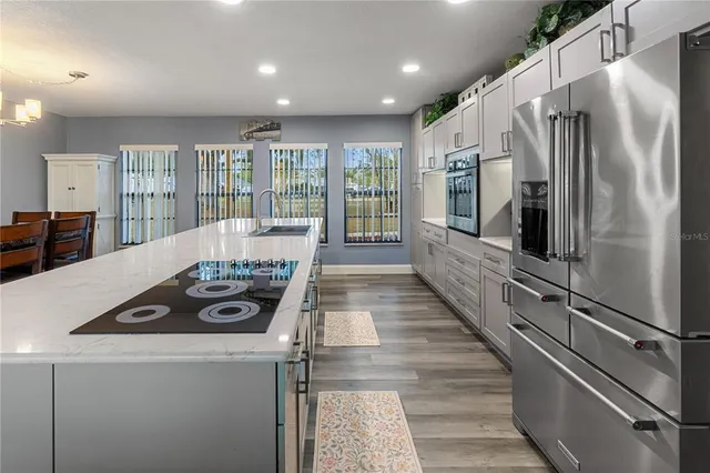 a large kitchen with stainless steel appliances granite countertop a refrigerator and a stove