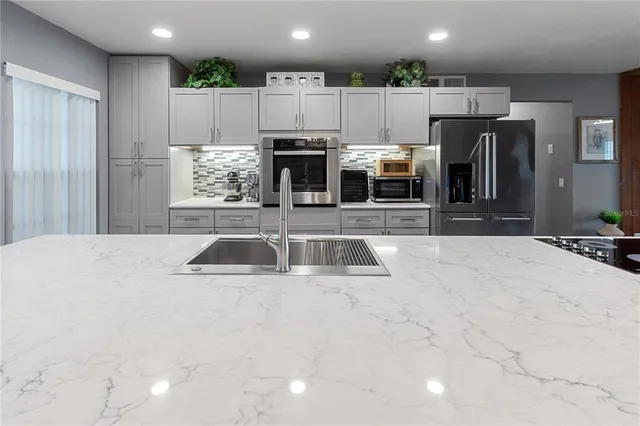 a kitchen with kitchen island a large counter top stainless steel appliances and cabinets