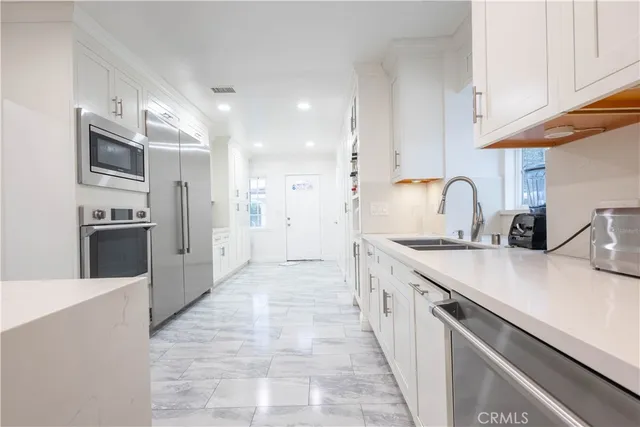 a living room with stainless steel appliances kitchen island granite countertop a sink and a microwave