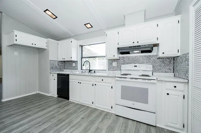 a kitchen with stainless steel appliances granite countertop a stove a sink and white cabinets