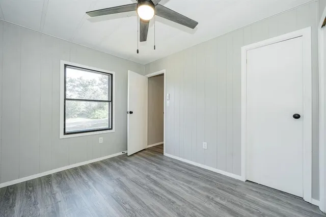 an empty room with wooden floor chandelier fan and windows