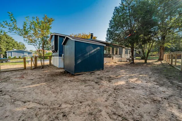 a view of backyard with large trees and wooden fence